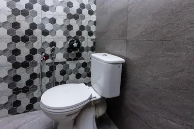 a bathroom with a toilet and a tiled wall at 13-Pax Vacation Retreats in Butterworth near Sunway Carnival in Perai