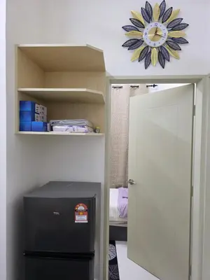 a room with a refrigerator and a clock on the wall at Aqimi Homestay in Seri Iskandar