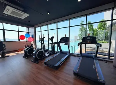 a gym with three treadmills in a room with windows at Iconic Regency by BNB4U in Bayan Lepas