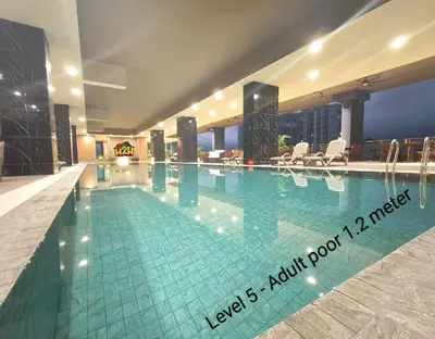 a large swimming pool in a hotel with chairs at ICC Suites Ipoh 202A by H2H in Ipoh