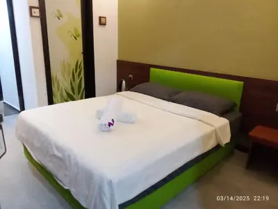 a bedroom with a bed with a green headboard at D GAYA HOTEL Cameron Highlands in Tanah Rata