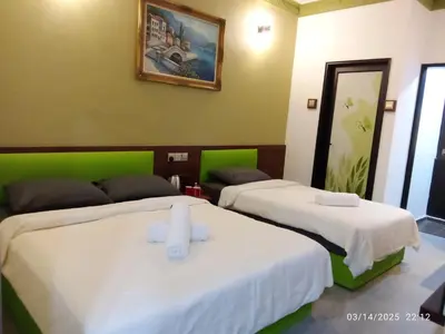 two beds in a room with green and white at D GAYA HOTEL Cameron Highlands in Tanah Rata