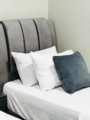 a bed with white pillows and a gray headboard at Jac Urban Suites Luxury & Premium Staycation 10pax in George Town
