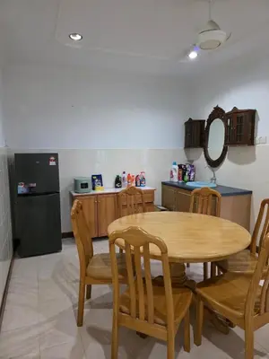 a kitchen with a table and chairs and a refrigerator at Permata Atiey Homestay in Seri Iskandar