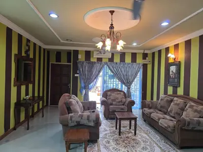 a living room with chairs and a couch and a chandelier at Permata Atiey Homestay in Seri Iskandar