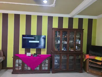 a living room with a flat screen tv and a table at Permata Atiey Homestay in Seri Iskandar