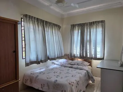 a bedroom with a bed and two windows at Permata Atiey Homestay in Seri Iskandar