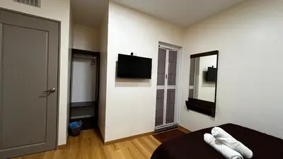 a room with a bed and a mirror and a television at Skye Apartment Hotel in Brinchang
