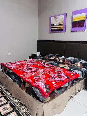 a bed with a red blanket on top of it at Lunas Indah Homestay in Lunas
