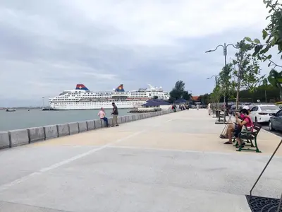 a cruise ship in the water with people sitting on benches at Georgetown Homestay in George Town