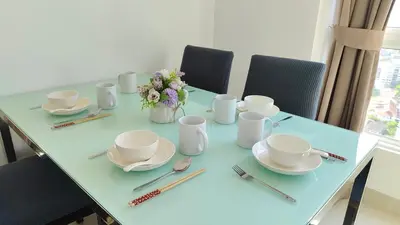 a table with cups and plates and a vase of flowers at High-Rise Suite with view-Near Gurney & Gleneagles in George Town
