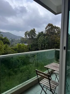 a balcony with a table and a view of the forest at Lily Dante in Tanah Rata