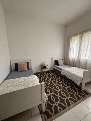 a bedroom with two beds and a rug at Lily Dante in Tanah Rata