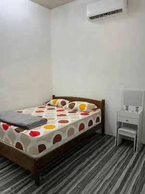 a bedroom with a bed and a night stand and a table at CK Homestay Parit Buntar Perak in Bagan Serai