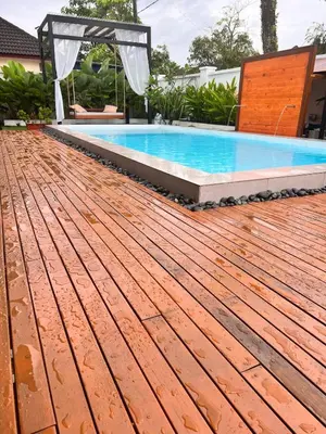 a swimming pool with a wooden deck next to a house at Dahlia Kulim Pool Homestay in Kulim