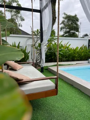 a swing by a swimming pool next to a house at Dahlia Kulim Pool Homestay in Kulim