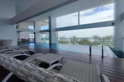 a room with chairs and a swimming pool in a building at Cozy Seaview Duplex Apartment at Sunrise Gurney in George Town