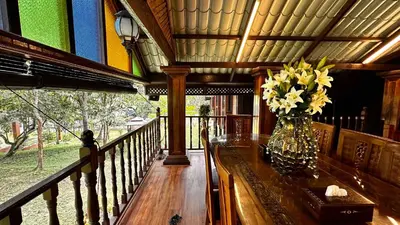 a vase of flowers on a table on a porch at Charming Nature Kampung Home for Family Getaways in Benta