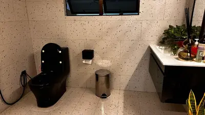 a bathroom with a black toilet and a sink at Charming Nature Kampung Home for Family Getaways in Benta