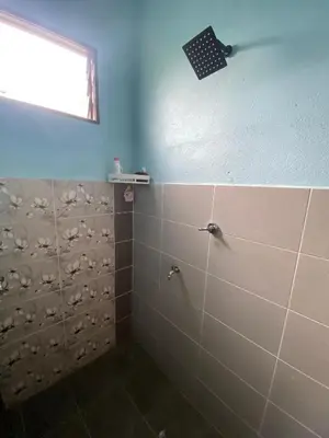 a bathroom with a shower with brown tiles and a window at Nabilah Homestay Labuh Banting in Kepala Batas
