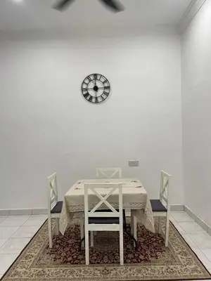 a table with two chairs and a clock on a wall at Nona Homestay in Parit Buntar