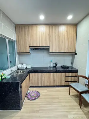 a kitchen with wooden cabinets and a black counter top at AYAAN PLATINUM Foosball Home at Quintet Apartment Free Parking in Tanah Rata