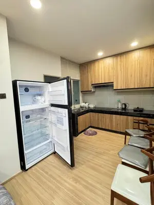 a kitchen with an open refrigerator and wooden cabinets at AYAAN PLATINUM Foosball Home at Quintet Apartment Free Parking in Tanah Rata