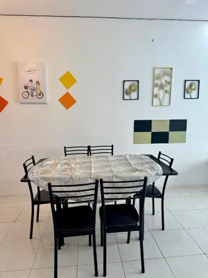 a table and chairs in a room with paintings at AYAAN LAVISH PRIMA APARTMENT FREE WiFi in Tanah Rata