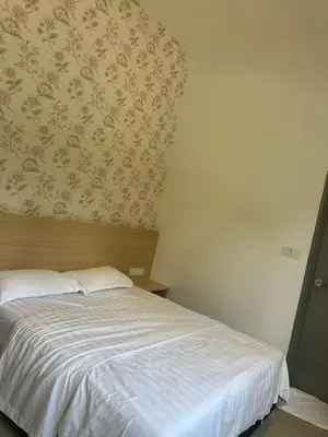 a bedroom with a white bed with a floral wallpaper at Adik Aisyah cameron semi-D goleden hill homestay in Brinchang