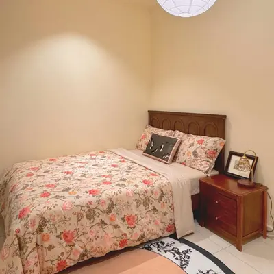 a bedroom with a bed and a wooden headboard and a table at The Heritage 3BR Apartment at Town Centre in Ipoh