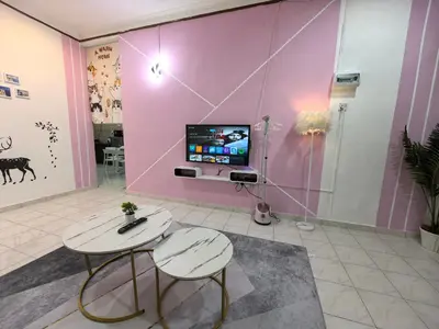 a room with two tables and a tv on a wall at Padang Serai Harmoni Homestay in Padang Serai