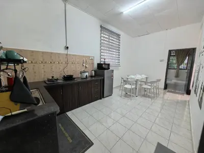a large kitchen with a table and chairs in it at Padang Serai Harmoni Homestay in Padang Serai