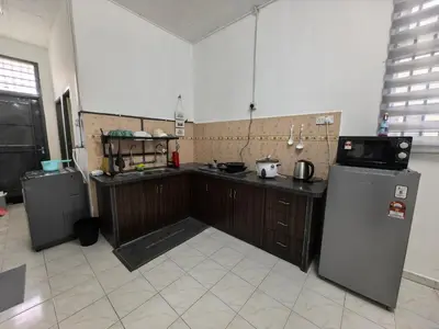 a kitchen with wooden cabinets and a refrigerator at Padang Serai Harmoni Homestay in Padang Serai