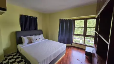 a bedroom with a white bed with blue curtains at Highlanders Apartment in Tanah Rata