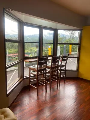 a dining room with a table and chairs and windows at Highlanders Apartment in Tanah Rata