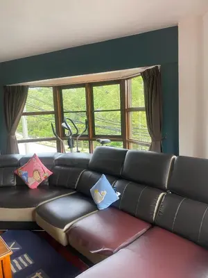 a living room with a black leather couch with pillows at Highlanders Apartment in Tanah Rata