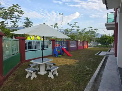 a picnic table with an umbrella and a playground at HOMESTAY KLeMERU E POH in Chemor