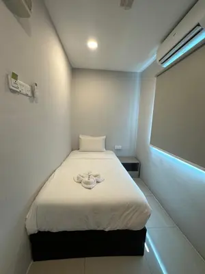 a small room with a bed with a white blanket at Georgetown Hotel in George Town