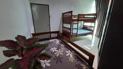 a room with a bed and a chair and a plant at 2BR Airport Panoramic View Family Suite in Bayan Lepas