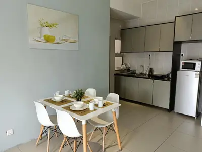 a kitchen with a table and chairs and a white refrigerator at Family Suite at Cameron Golden Hills in Brinchang