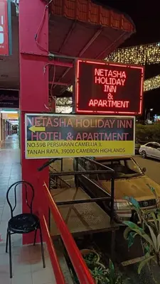 a sign for a restaurant with a chair on a sidewalk at Cool view hostel in Tanah Rata