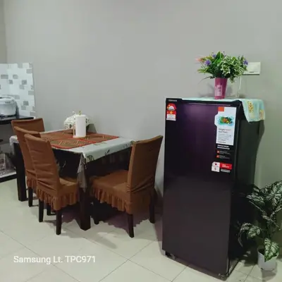 a kitchen with a table and a black refrigerator at d'esaku homestay in Penaga