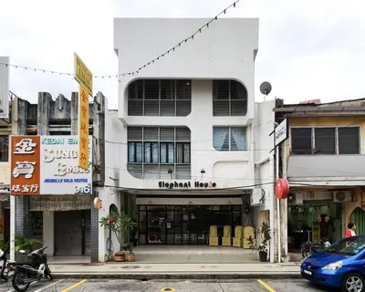 a white building on a street with a car parked in front at Elephant House Hotel in George Town