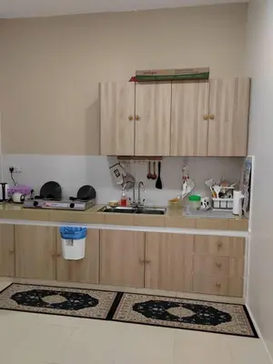 a kitchen with wooden cabinets and a sink at Ana Homestay in Seri Manjung