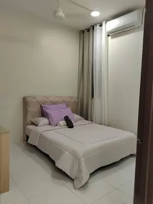 a white bedroom with a bed with purple pillows at Ana Homestay in Seri Manjung