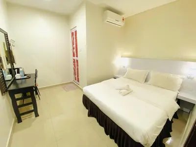a bedroom with a large white bed and a desk at Sunsega Hotel in Perai