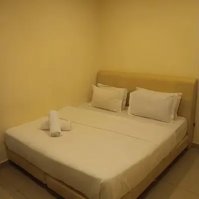 a bed with white sheets and pillows in a room at Sunsega Hotel in Perai