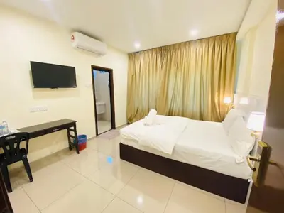a bedroom with a bed and a desk and a television at Sunsega Hotel in Perai