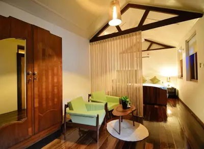 a living room with green chairs and a bed at Sarang Paloh Heritage Stay in Ipoh