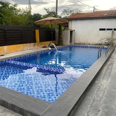 a large blue swimming pool with an umbrella at Darainhomestay in Gua Sai